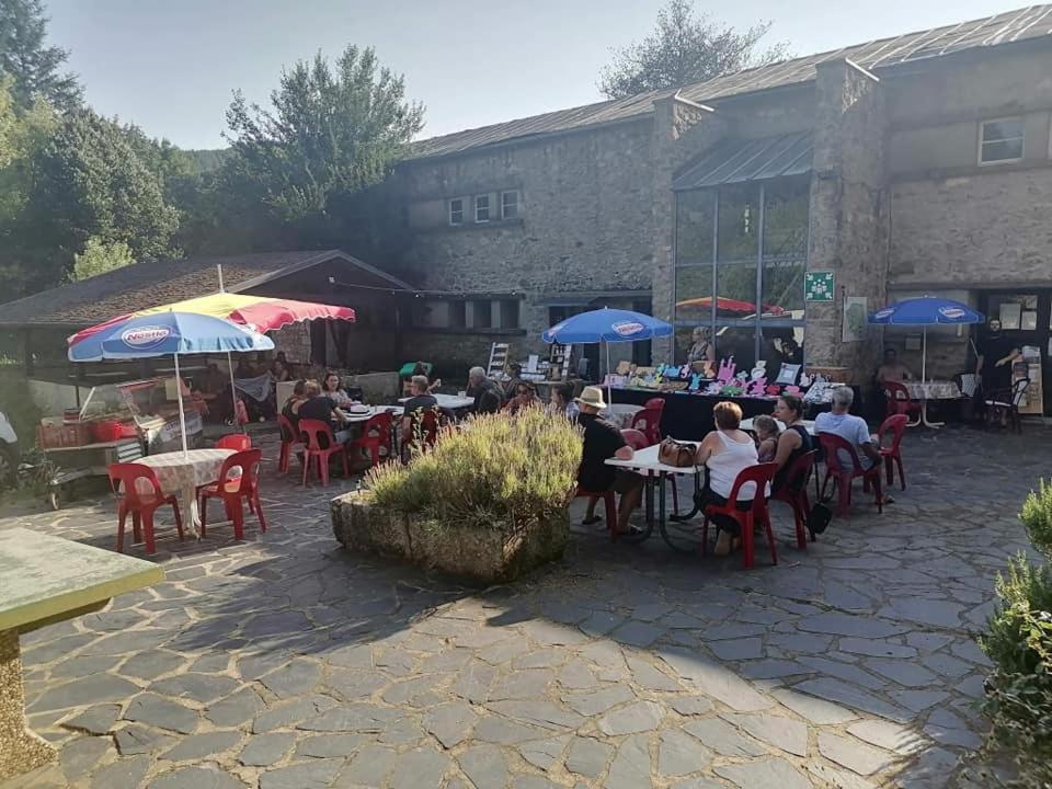 un gruppo di persone seduti a tavoli con ombrelloni di Chalet privé résident - camping la raviège a La Salvetat