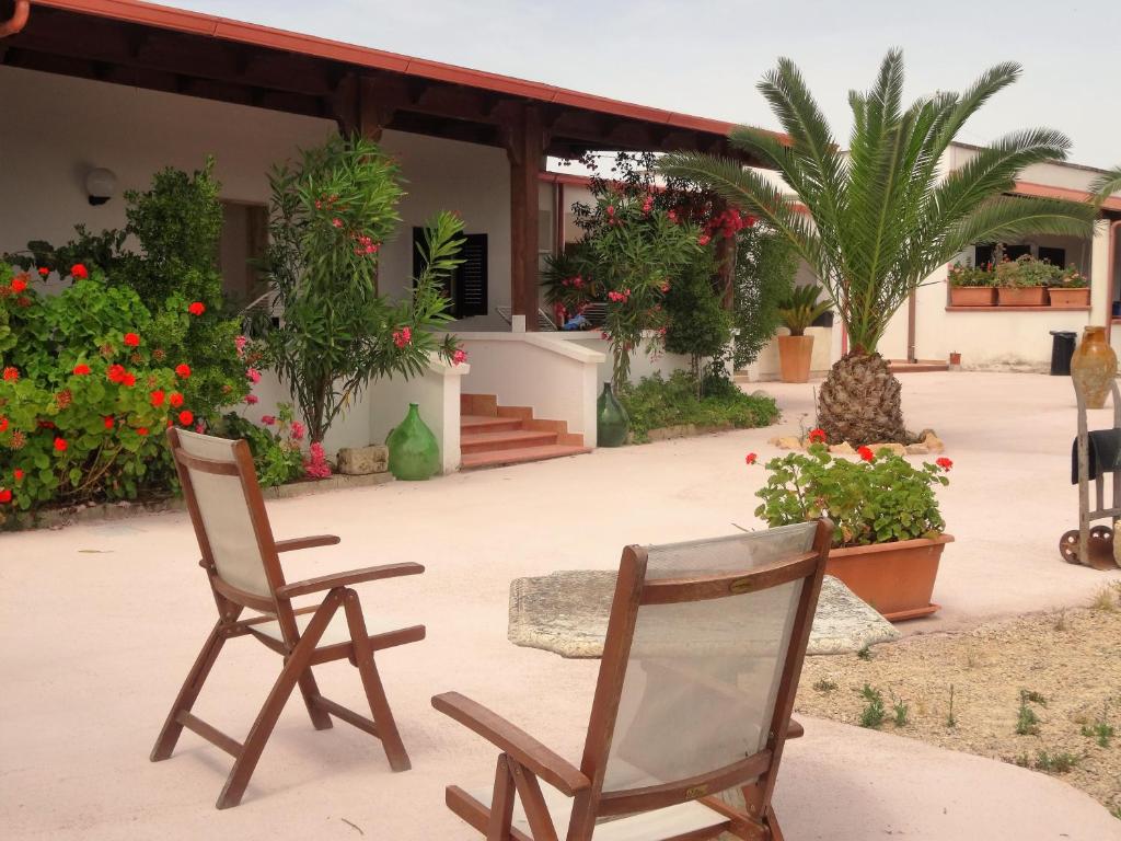 two chairs sitting in front of a house with flowers at Casa Colonica Liliane B&B in Porto Cesareo
