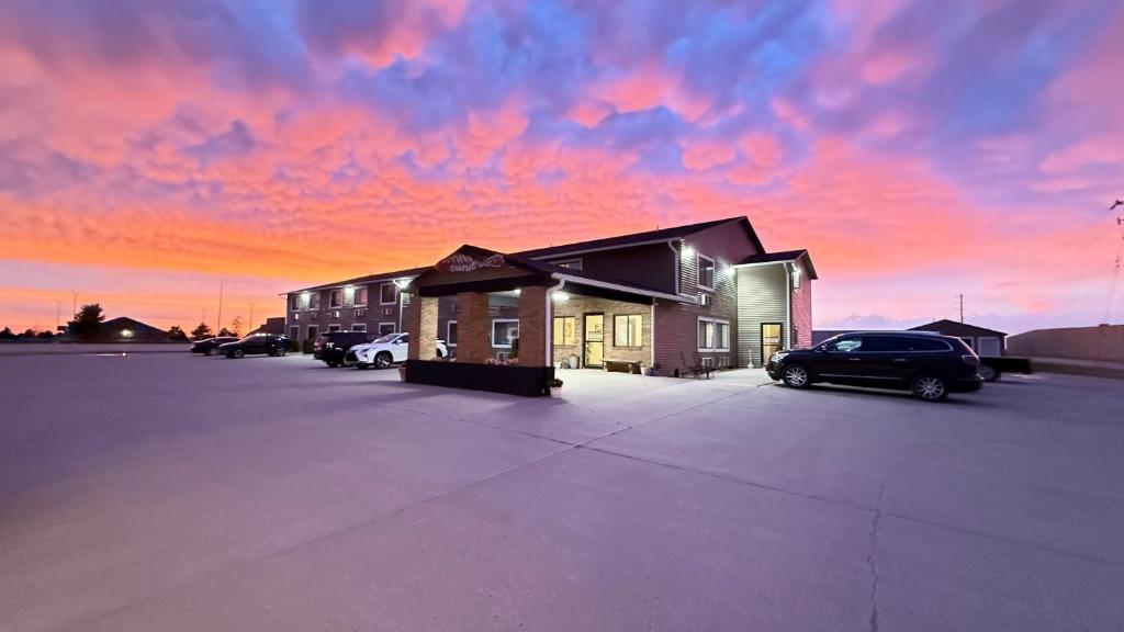a building with cars parked in a parking lot with a sunset at clarion hometown inn in Clarion