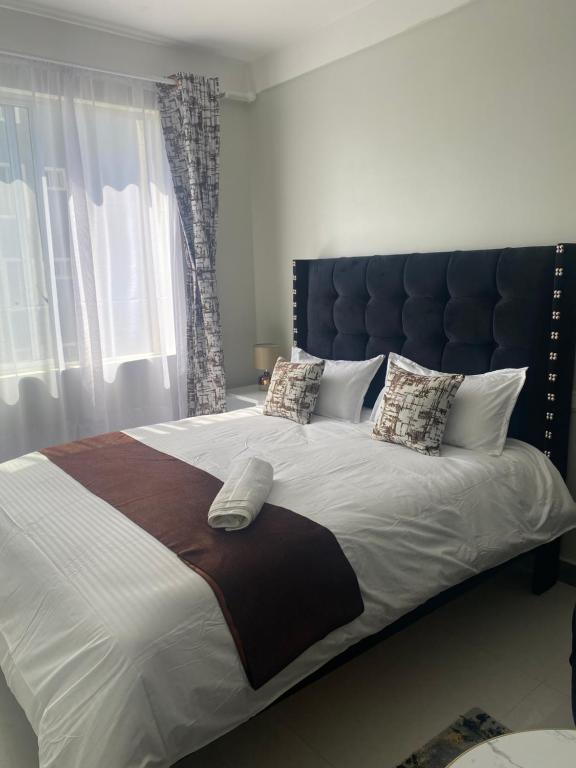 a bedroom with a large bed with a large headboard at Kaya Homes , Studio 23 mins to JKIA in Nairobi