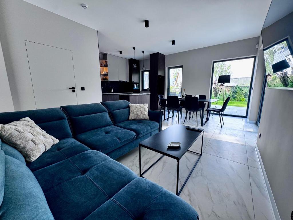 een woonkamer met een blauwe bank en een tafel bij Marina Dziwnow Premium Haus in Dziwnów