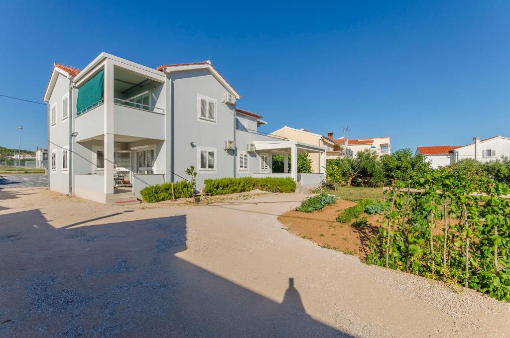 ein großes weißes Haus mit einer Auffahrt in der Unterkunft Apartments Quokka in Tribunj