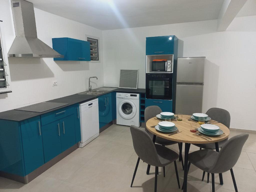 a kitchen with blue cabinets and a table with chairs at Flambroyant in Fort-de-France