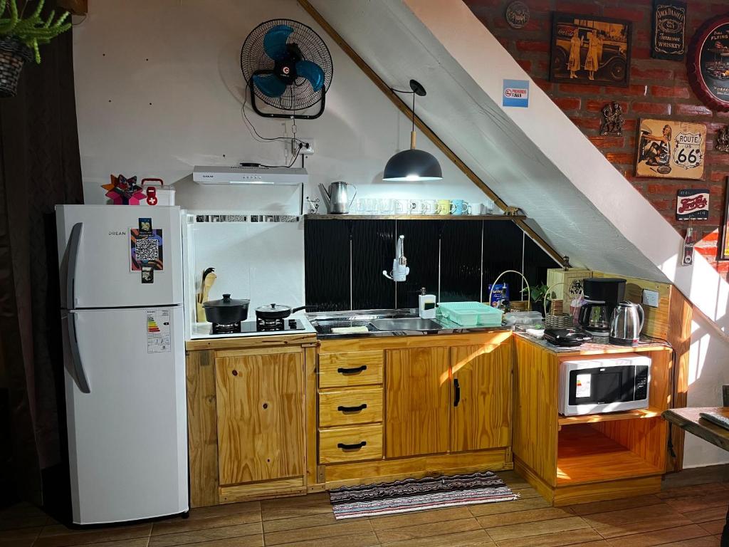 a kitchen with a white refrigerator and wooden cabinets at Guazú Departamentos in Puerto Iguazú