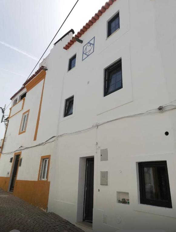 a white building with black windows on a street at Casa da Orada in Avis