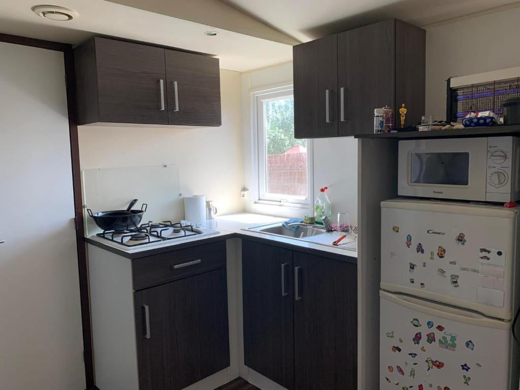 eine Küche mit braunen Schränken, einer Mikrowelle und einem Kühlschrank in der Unterkunft Casa prefabricada in El Casar de Escalona