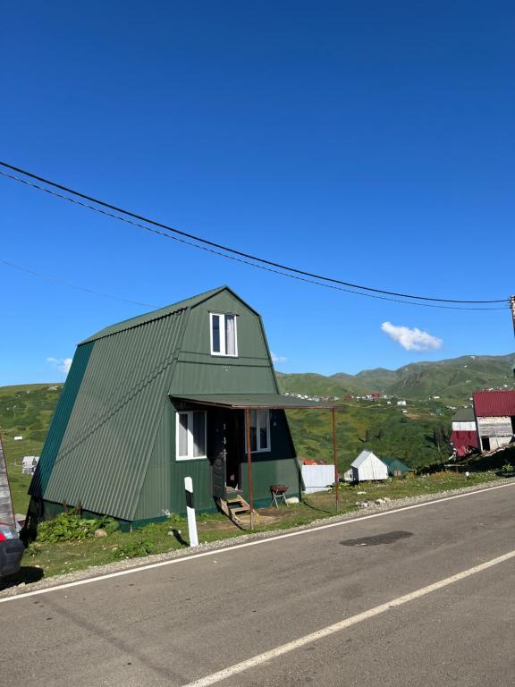 a green building on the side of a road at Cloudtop House - Gomismta in Gomi