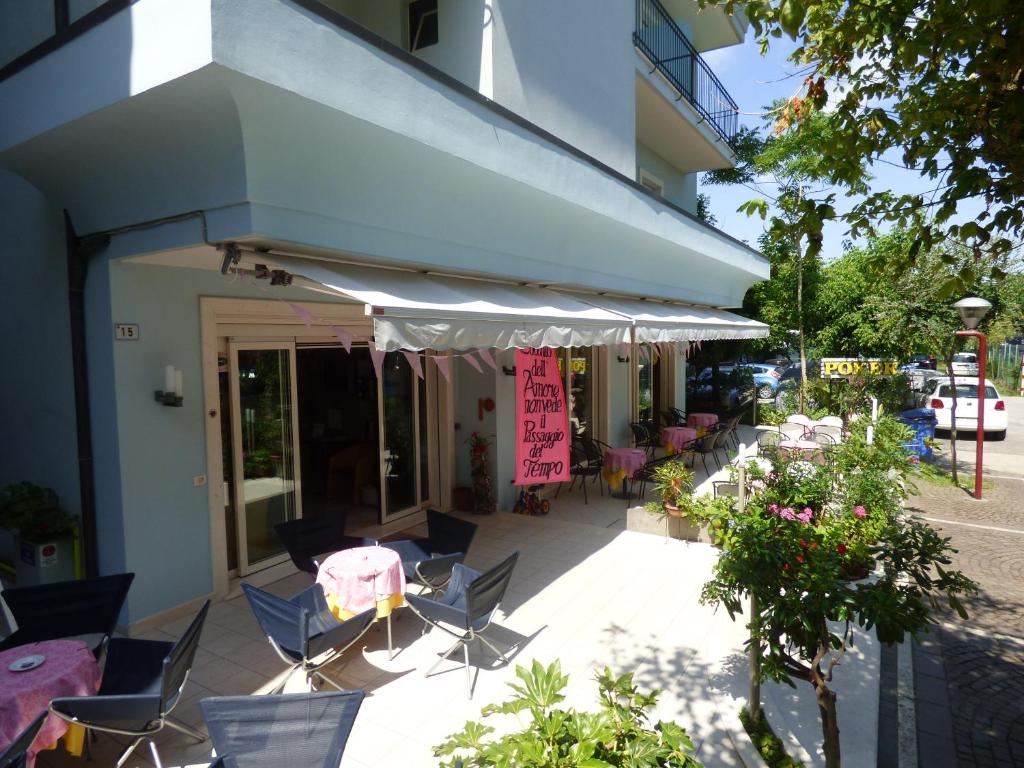 un patio con sillas y mesas y un edificio en Hotel Poker, en Misano Adriatico