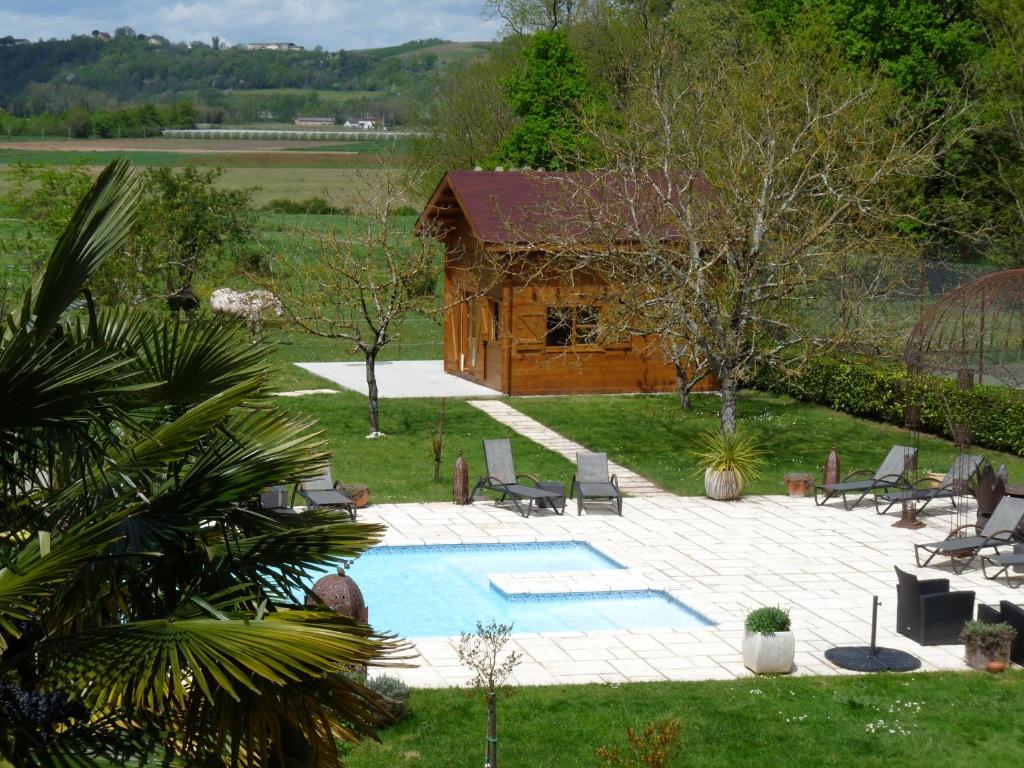 uma piscina num quintal com um chalé de madeira em Les Chalets du Manoir em Montauban