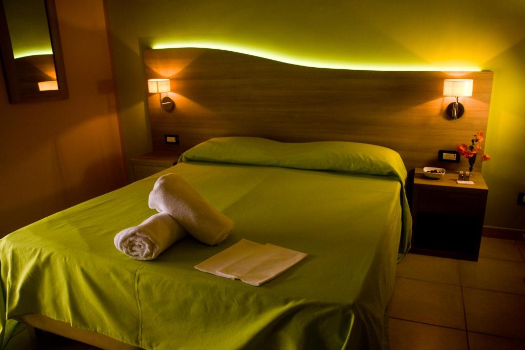 una camera da letto con un letto verde con due asciugamani di B&B Liberty a Messina