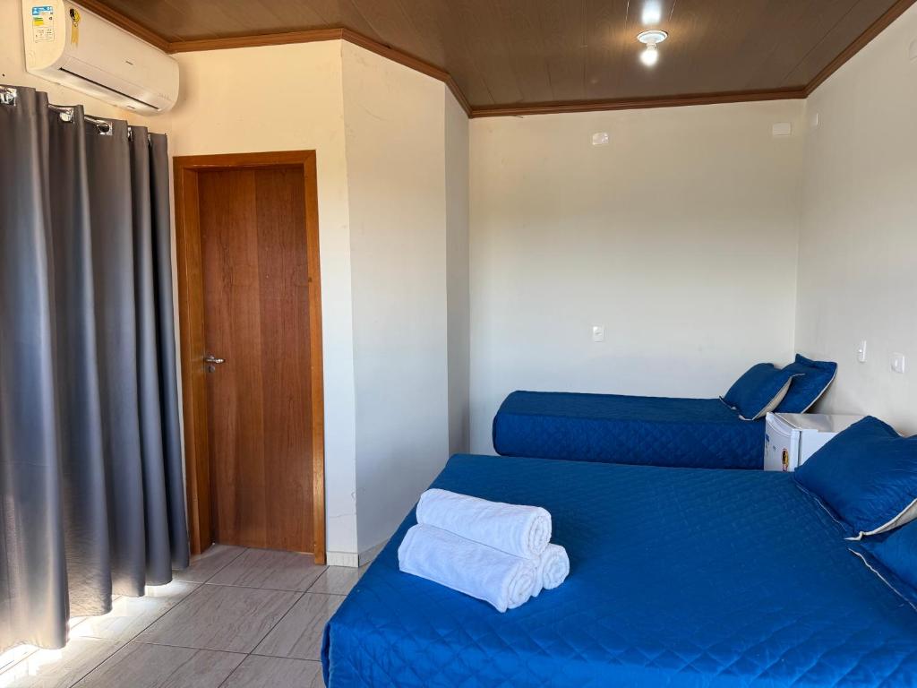 ein Schlafzimmer mit einem blauen Bett und einer Holztür in der Unterkunft Chácara Cidade da Divina Misericórdia in Araucária