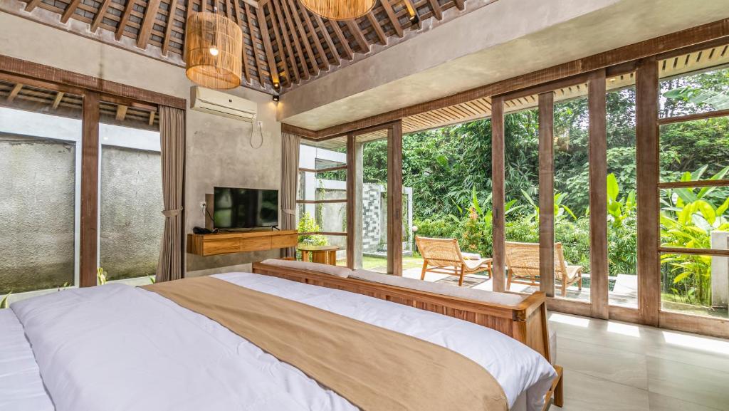a bedroom with a bed and a tv and windows at Anggrek villa Ubud in Ubud