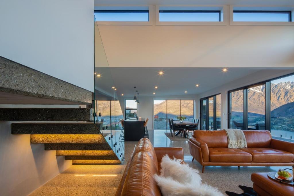 a living room with leather furniture and a staircase at Sky Villa A in Queenstown