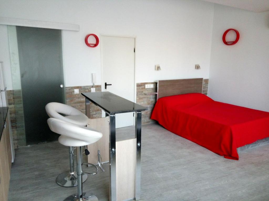ピネダ・デ・マールにあるApartamentos Bcntourismのベッドルーム1室(赤いベッド1台、テーブル、椅子付)