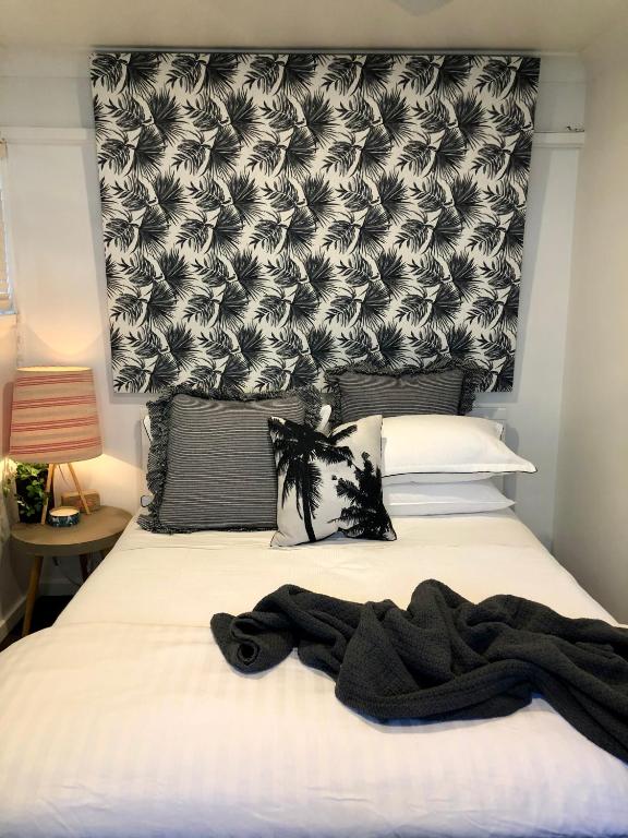 a bedroom with a bed with a black and white headboard at Allambie Guest House in Frenchs Forest