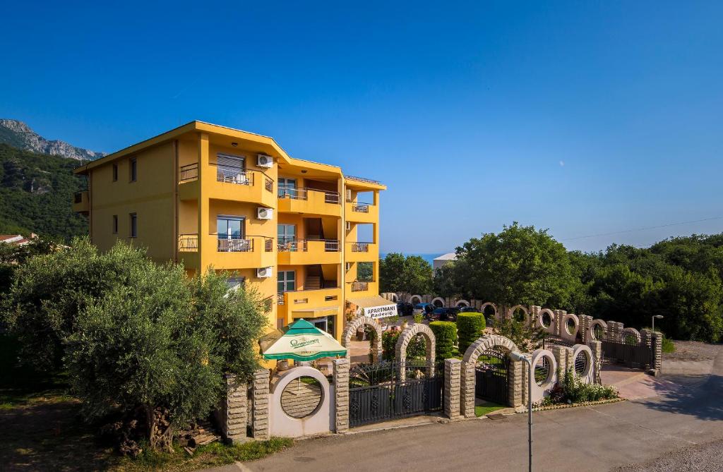 a yellow building with a fence in front of it at Apartments Radević in Budva