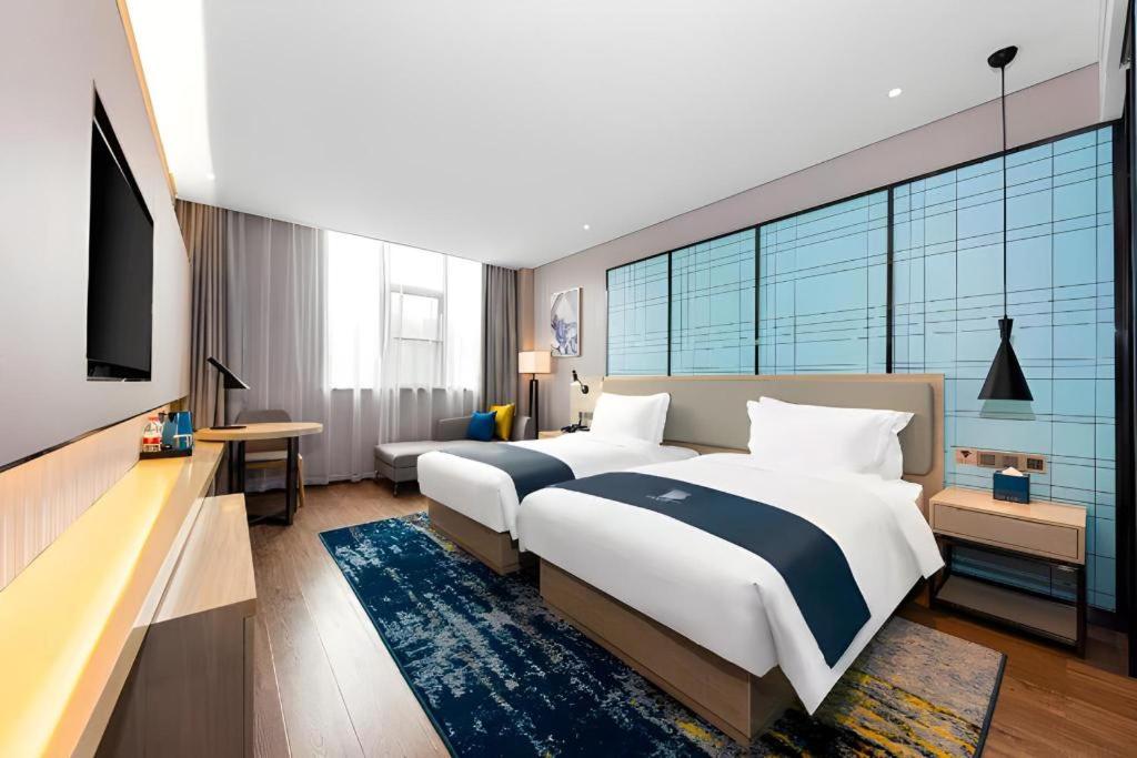 Un dormitorio con una cama grande y un televisor. en Echarm Hotel Wuhan Plaza Wansongyuan, en Wuhan
