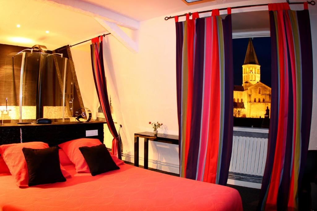 - une chambre avec un lit doté de rideaux colorés et d'une fenêtre dans l'établissement Hotel de la Basilique, à Paray-le-Monial