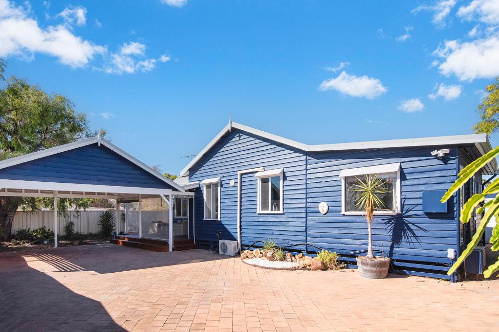 a blue house with a palm tree in front of it at Seashells Beach house on Dorset in Busselton