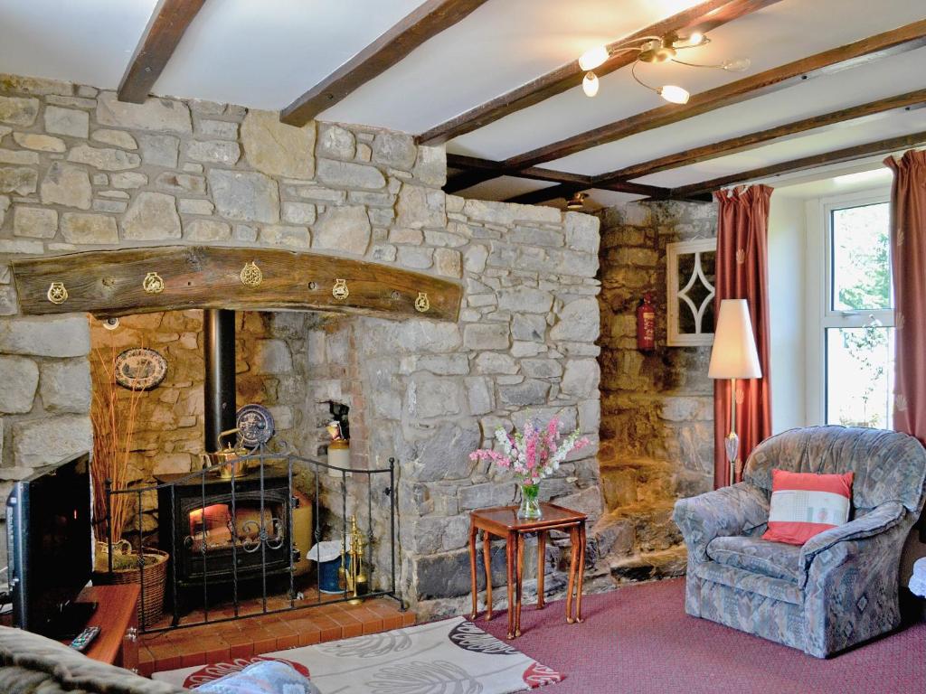 a living room with a stone wall with a fireplace at Murton Farm Cottage in Bishopston