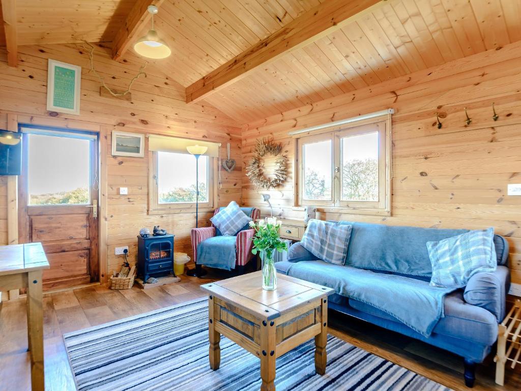 a living room with a blue couch and a table at Buttercup Lodge in Broomhill