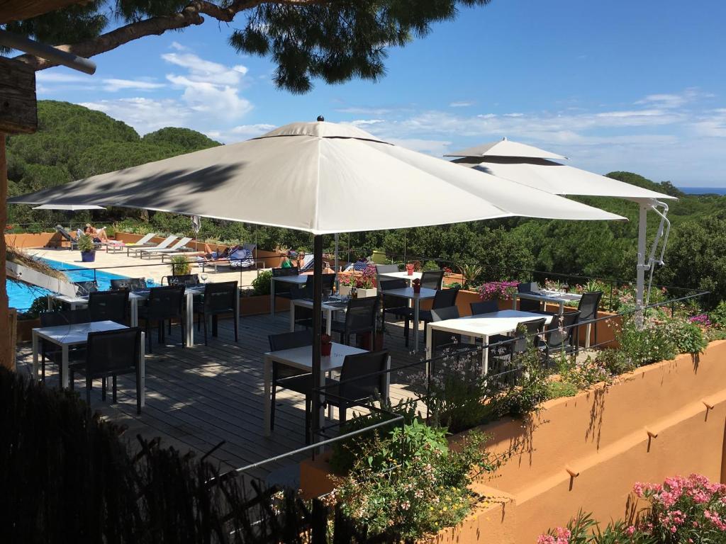 a patio with tables and umbrellas next to a pool at Hôtel les Bouis - Vue mer in Saint-Tropez