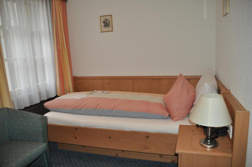 a bed in a room with a lamp and a chair at Hotel Engelberg "mein Trail Hotel" in Engelberg