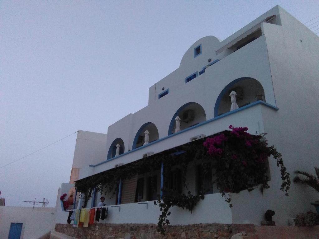 un edificio blanco con un balcón con flores. en Antonia Rooms, en Anafi