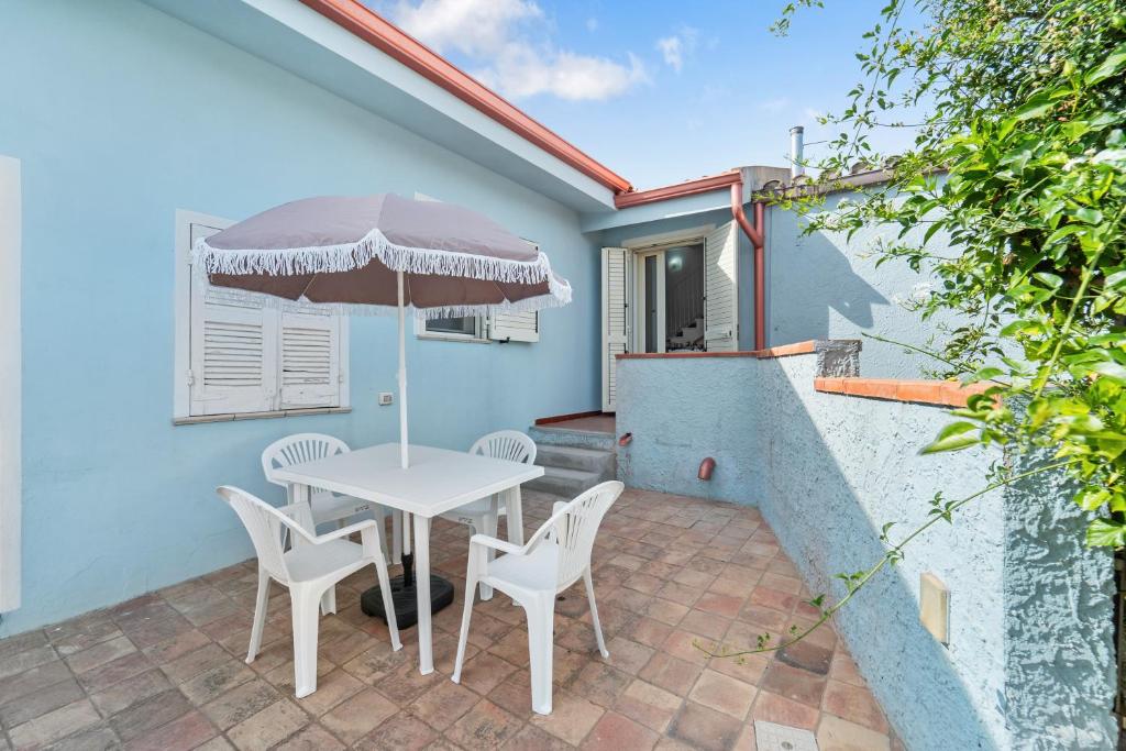 a patio with a table and chairs and an umbrella at Domu Istella in SantʼAnna Arresi