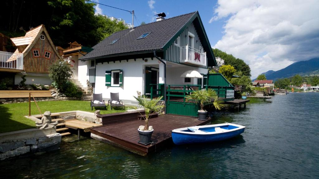 a house on a dock with a boat on the water at Smileys Seehäuschen in Seeboden
