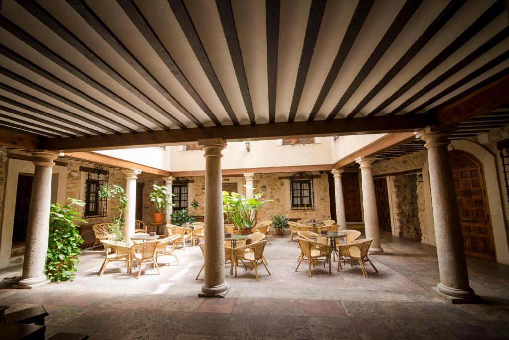 a patio with tables and chairs under a wooden ceiling at Hospedería Real Casona la Beltraneja in Belmonte