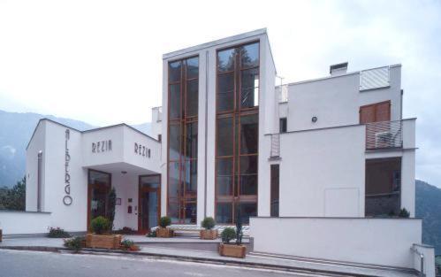 a large white building with a mountain in the background at Hotel Rezia in Sondalo