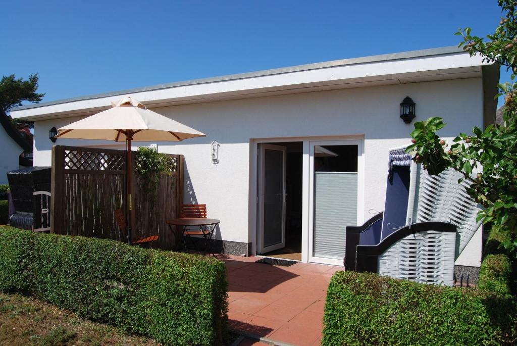 a white house with an umbrella and a patio at Ferienwohnung Hiddensee in Vitte in Vitte