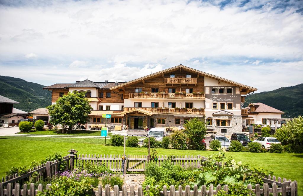 a large building with a fence in front of a yard at Hotel Winterbauer in Flachau