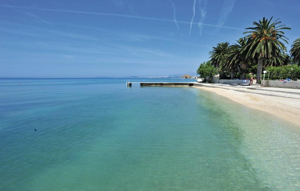 a beach with turquoise water and palm trees at Apartments Dalmacija in Podstrana