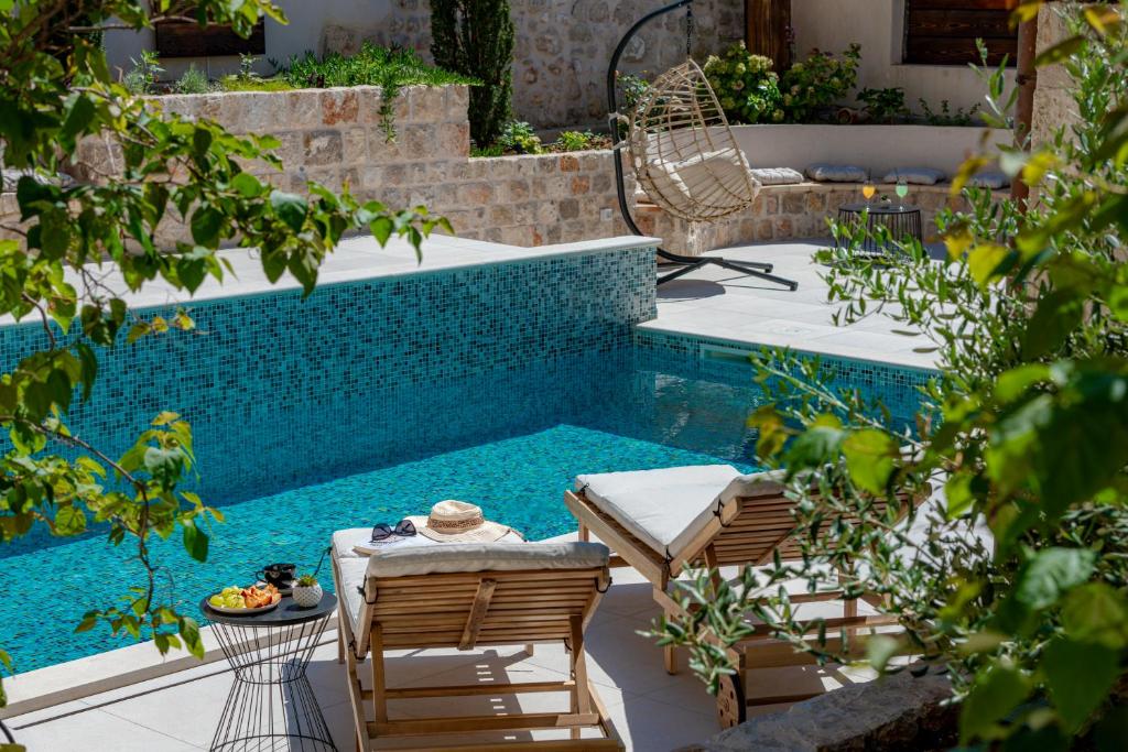 a swimming pool with two chairs and a table next to it at Luxury villa Lia in Dubrovnik