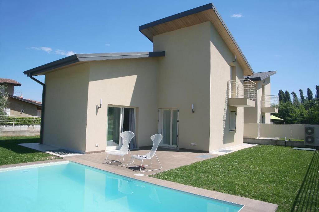 a house with two chairs and a swimming pool at Le Golfette - Ville al Golf in Manerba del Garda