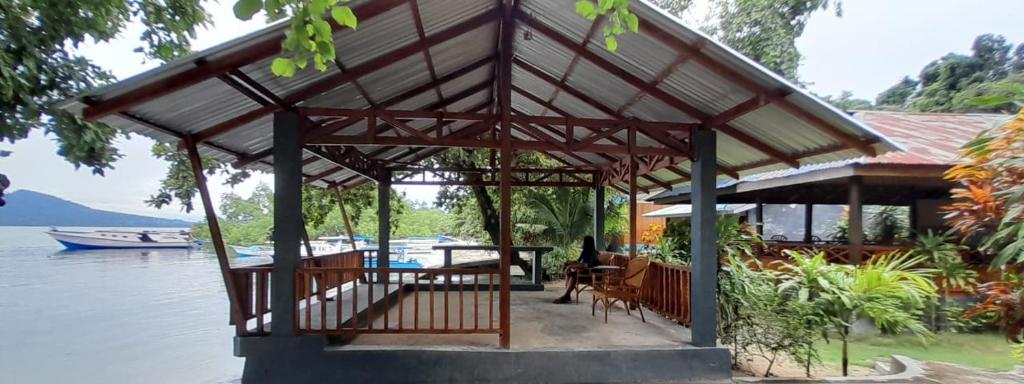 a pavilion with a table and chairs on the water at Bunaken Sunrise Beach in Manado