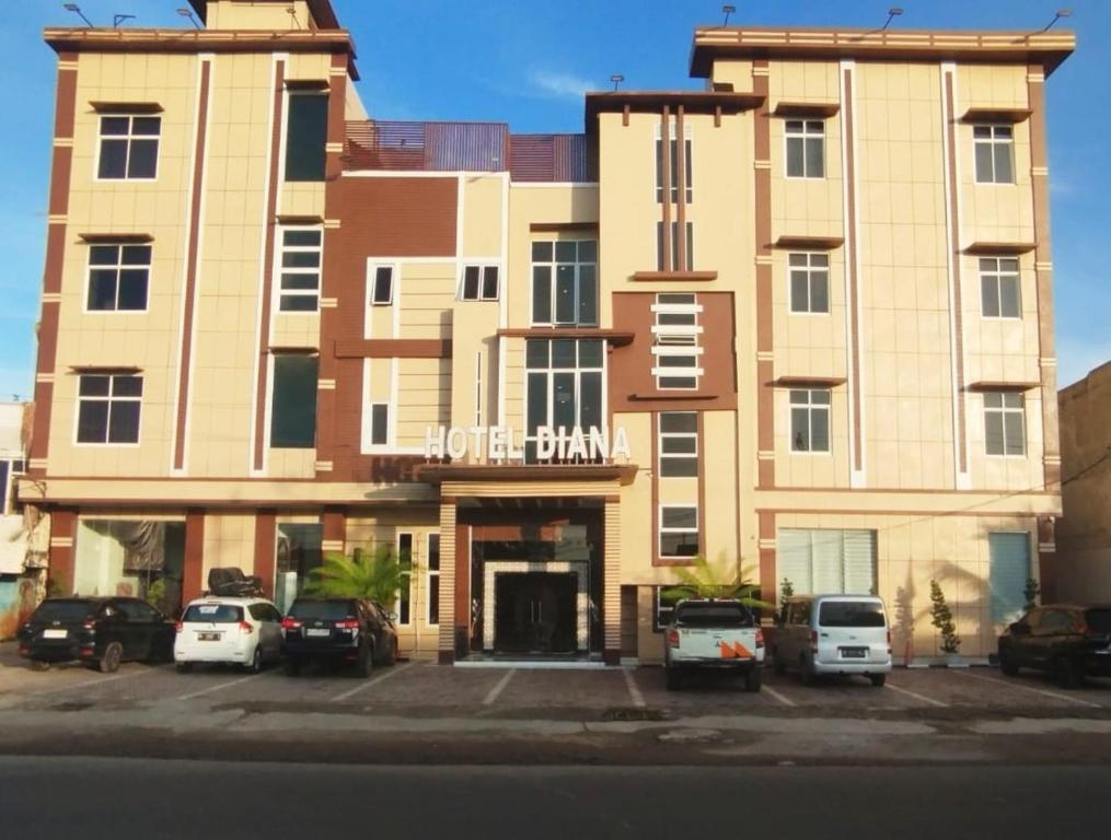 a large building with cars parked in a parking lot at Hotel Diana in Lhokseumawe