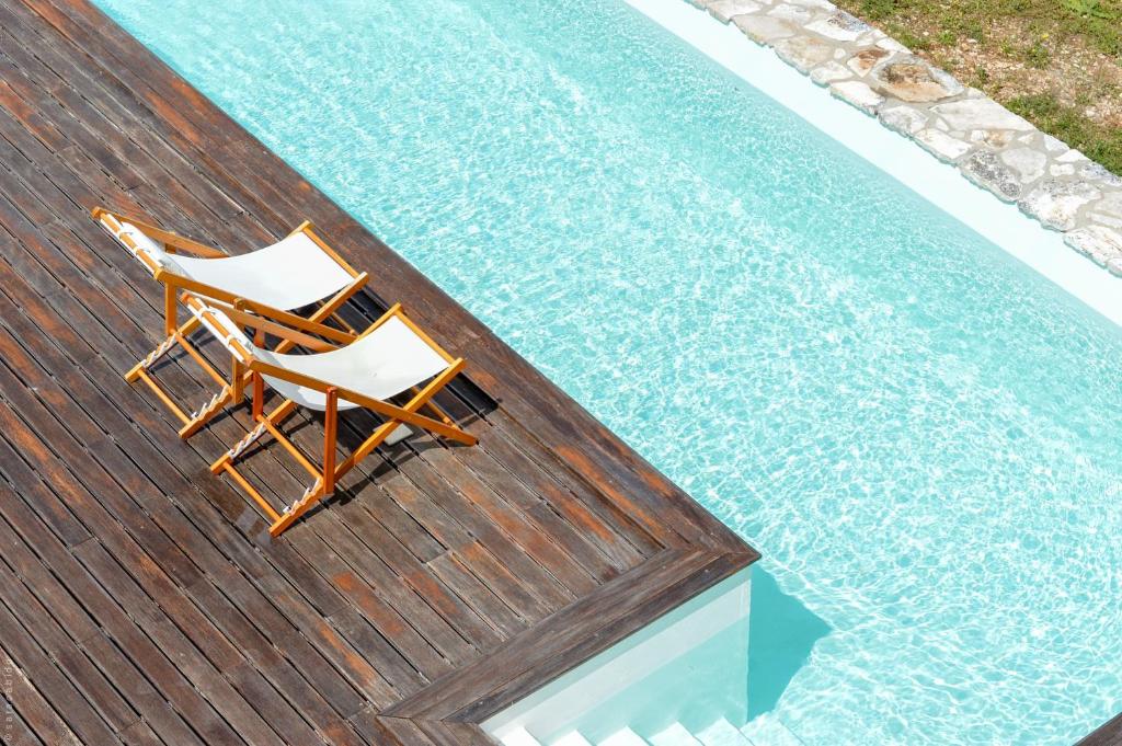 two chairs sitting on a deck next to a swimming pool at Retiro do Bosque Country House in Minde