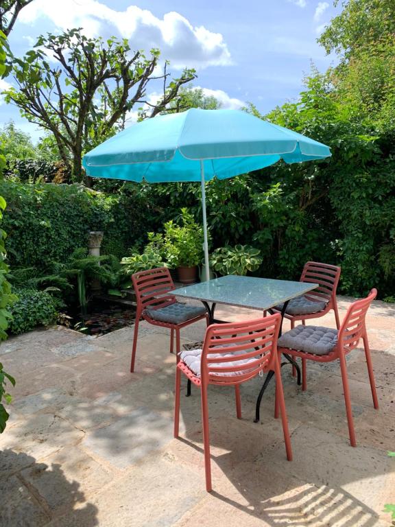 a table with two chairs and a blue umbrella at Appartement près de DOLE in Menotey