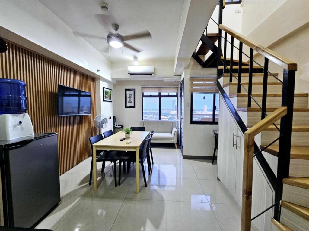 a kitchen and dining room with a table and a staircase at Mabolo Garden Flats Loft by Cebu Getaway in Sampong