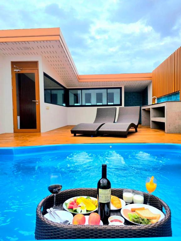 a pool with a table of food and a bottle of wine at Enjoy private pool villa in Chiang Mai