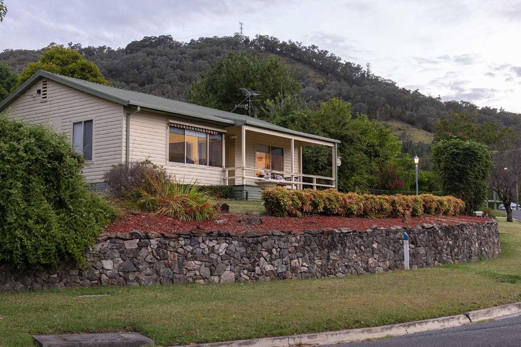 une petite maison avec un mur de pierre devant dans l'établissement Cosy Candlewick Cottage - A Mount Beauty Delight, à Mount Beauty