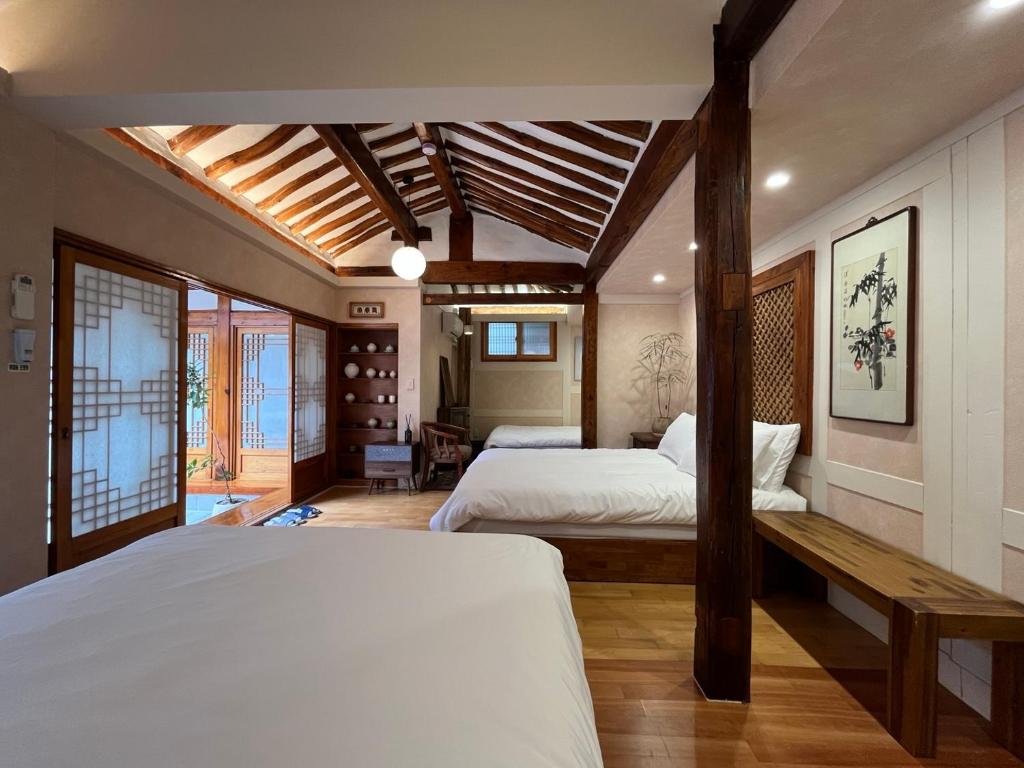 ein Schlafzimmer mit 2 Betten und einer Bank darin in der Unterkunft Seoul Bukchon Homi Hanok in Seoul