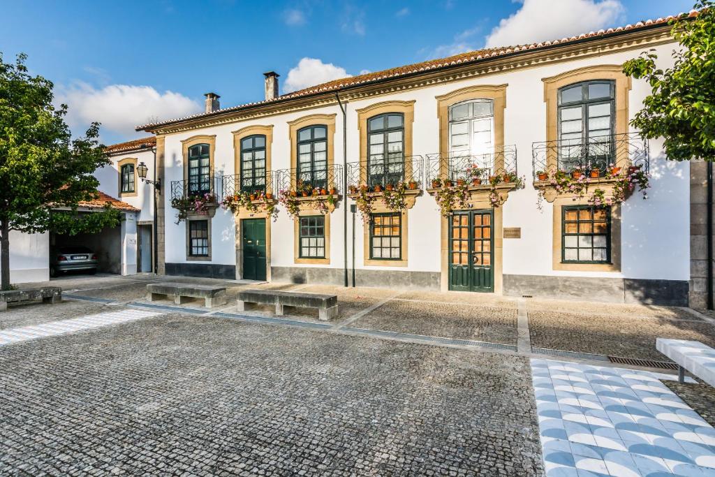 una vista exterior de un gran edificio blanco con ventanas en S. Thomé Apts, en Ovar