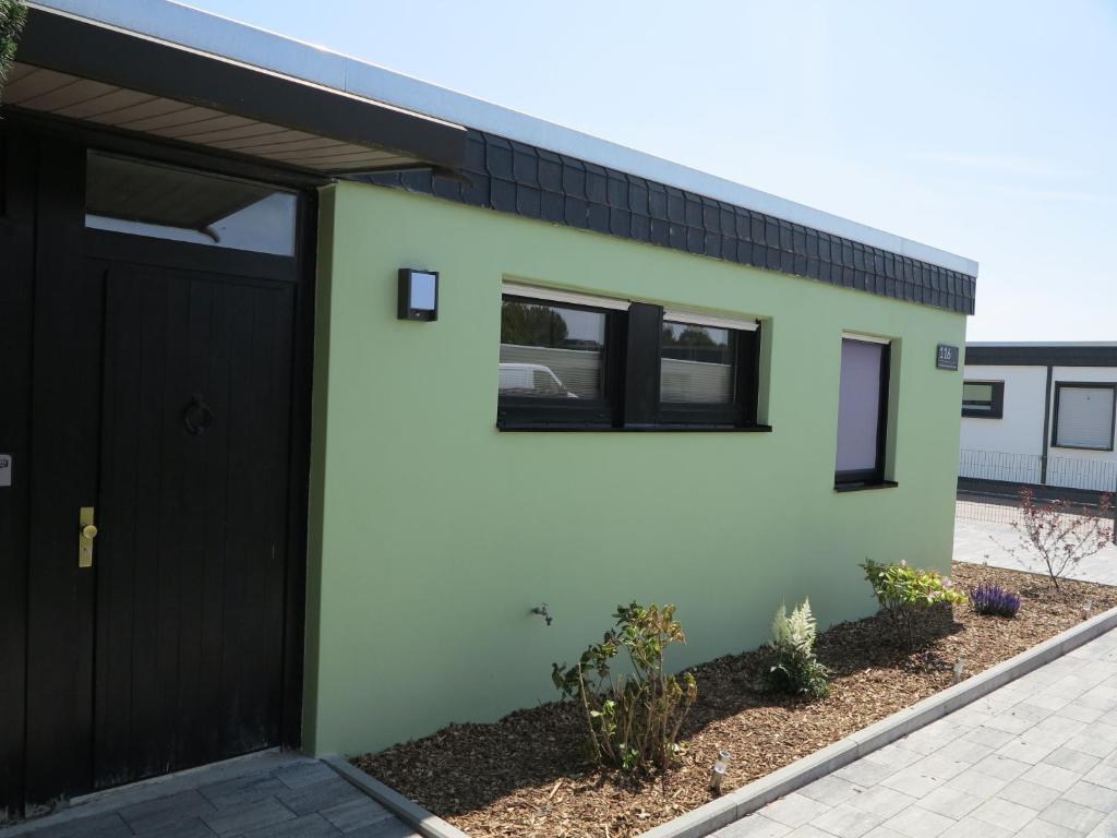 a green and black house with a black garage at Nordseeferienhaus Emma Tossens in Butjadingen