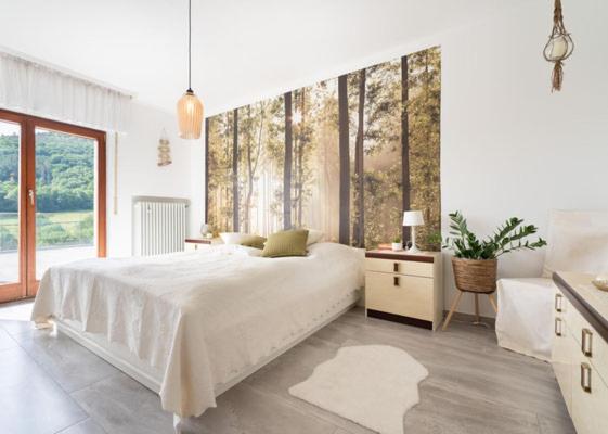 a white bedroom with a bed and a large window at Ferienhaus Burgblick in Hürtgenwald