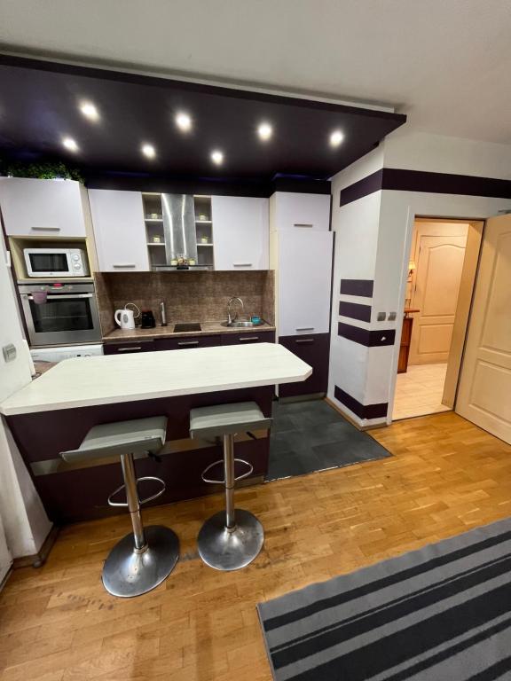 a kitchen with a white counter and two stools at Varna Cathedral Apartments in Varna City