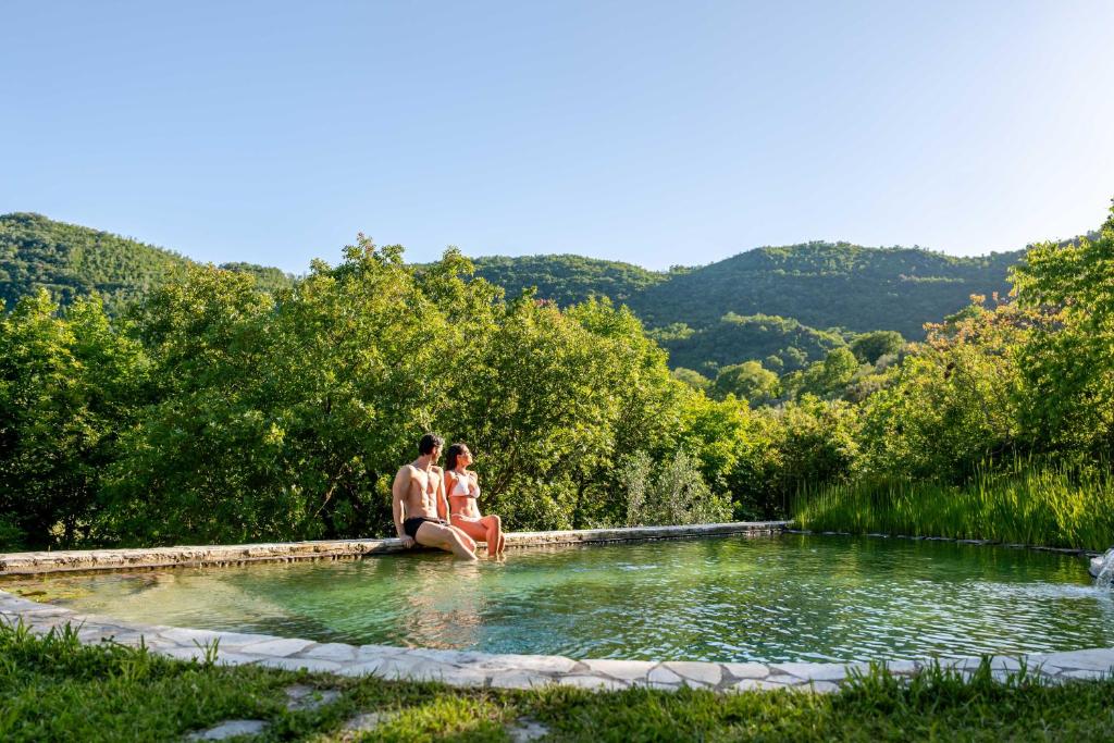 two people sitting in a pool of water at Respiro Umbria, 1500s Villa with Unique Biopool in Spoleto